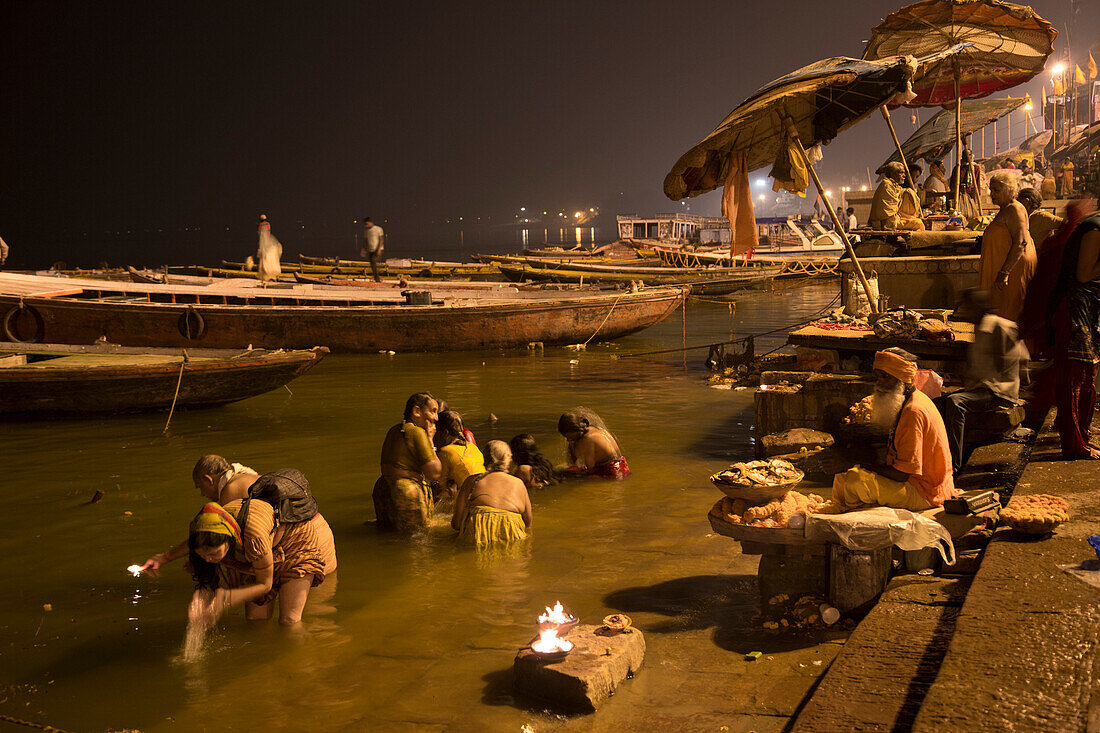 People wash themselves and Holy man prays at Dasaswamedh Ghat alongside Ganges river at dawn, Varanasi, Uttar Pradesh, India