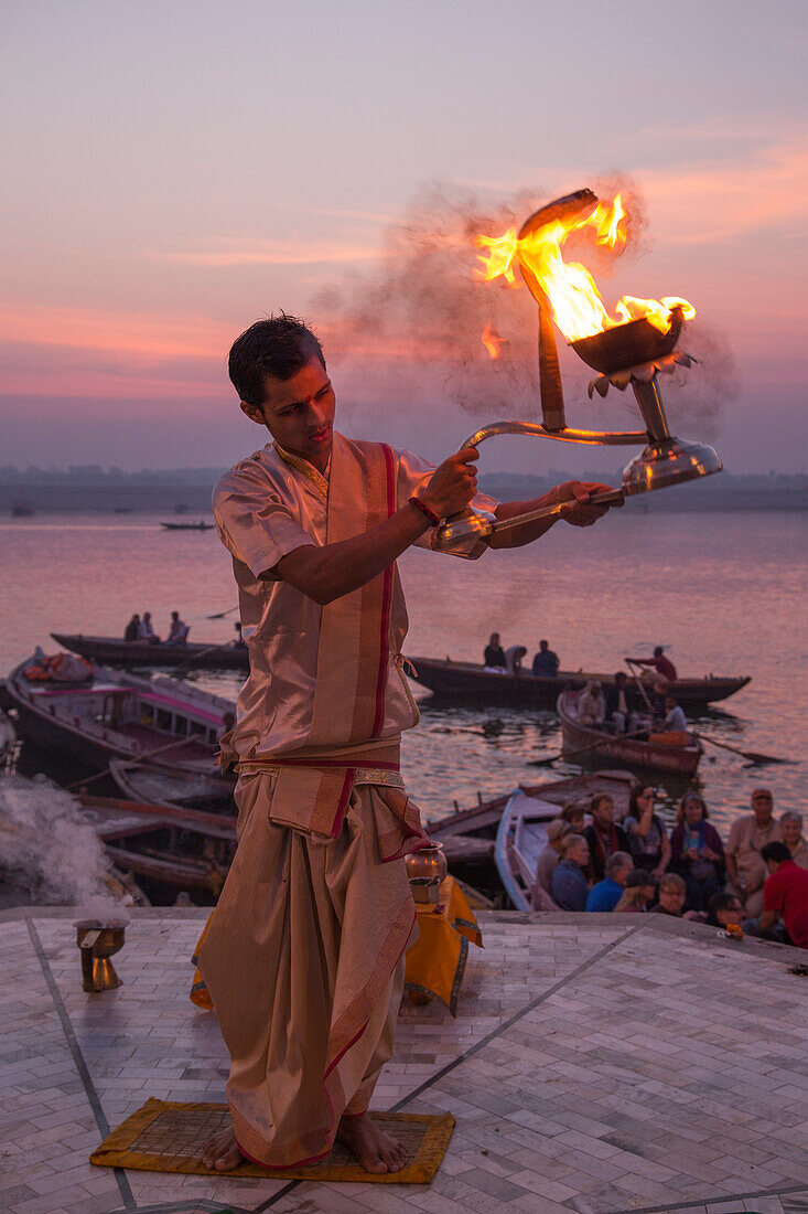 Hindu monk performs prayer ceremony at Dasaswamedh Ghat alongside Ganges river at sunrise, Varanasi, Uttar Pradesh, India