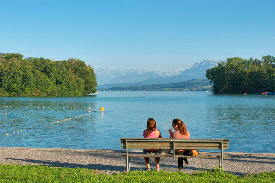 Bench on the bank of lake Sempachersee with Urner Alps, Sursee, Luzern, Switzerland, Europe