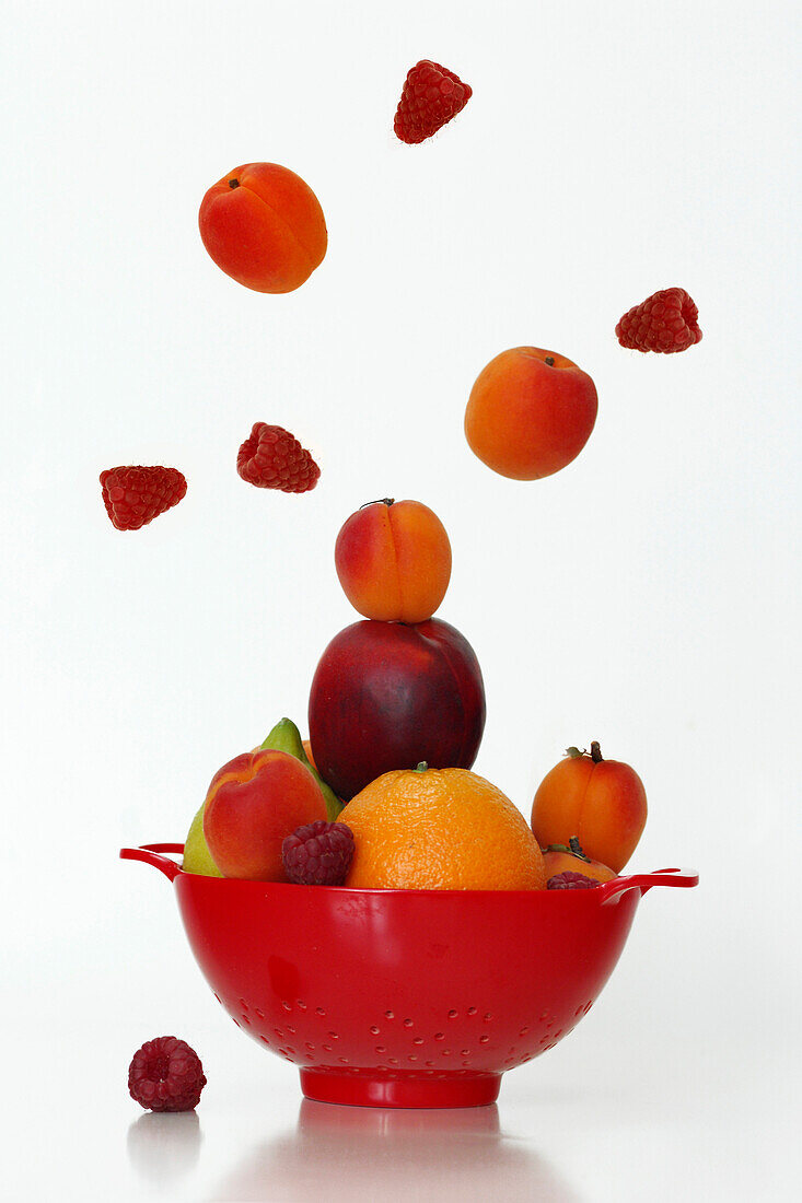 An Explosion Of Fruits (Nectarines, Apricots, Raspberries, Oranges And Lemons) In A Colander