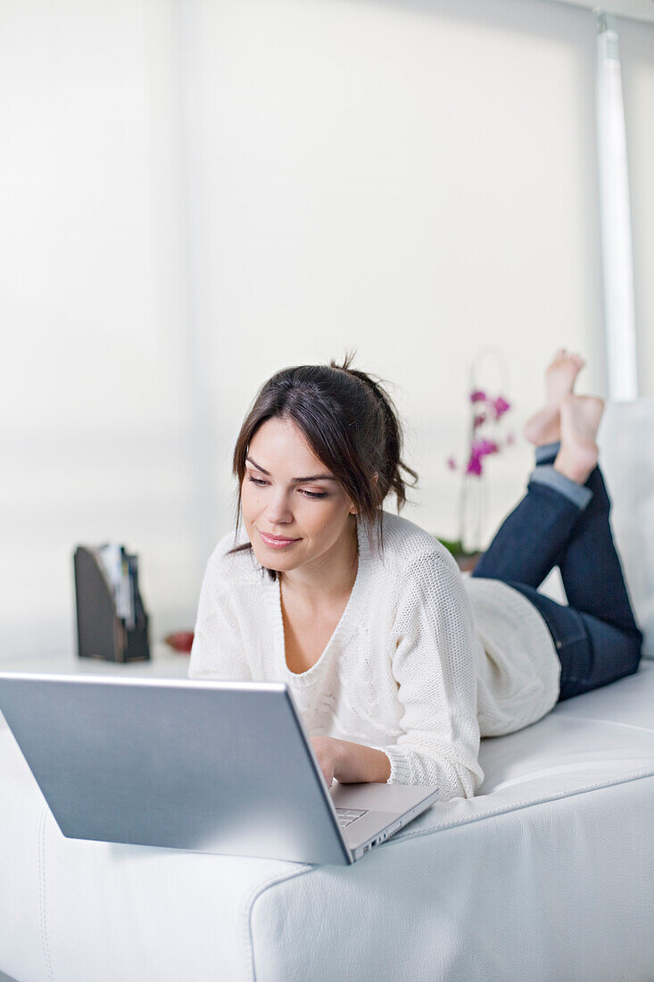 Beautiful brunette woman on a couch with computer