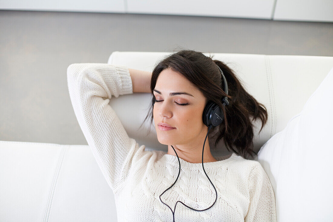 Pretty woman with headphones on the sofa