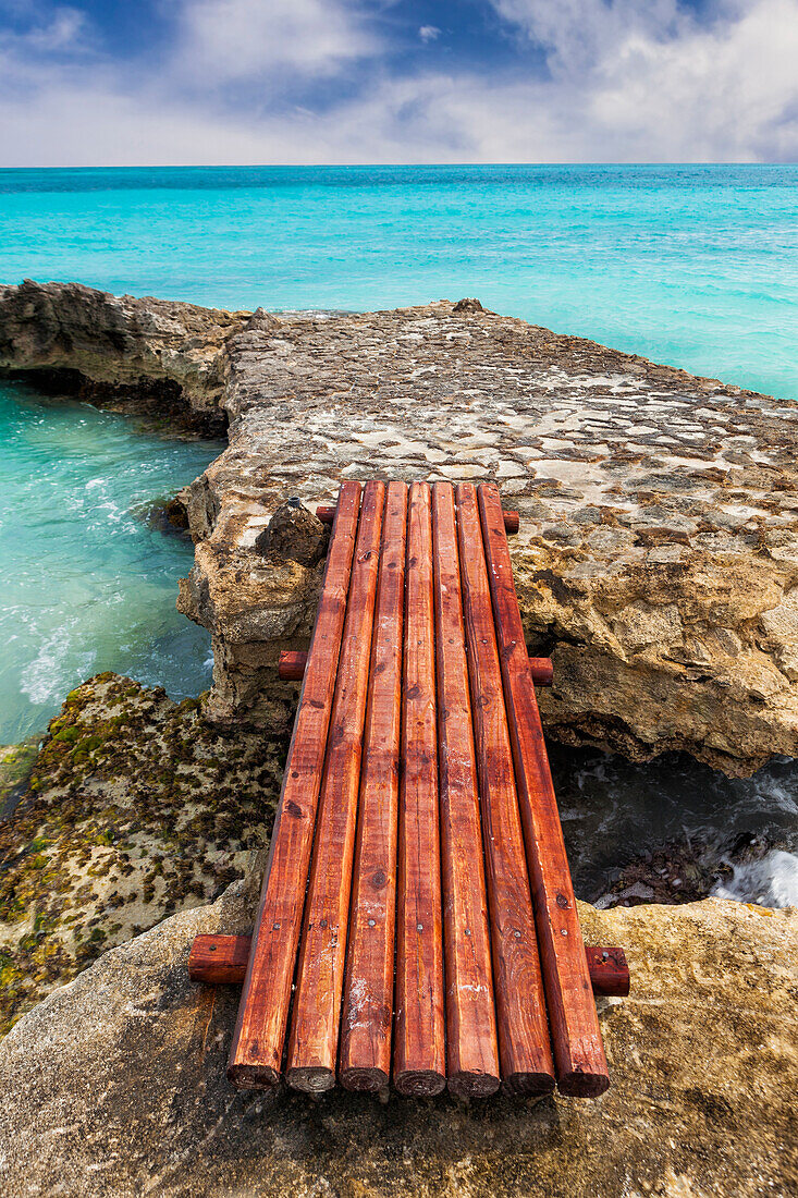 Wooden bridge across rocks on the coastline of Cancun. Erosion and rock formatons. Planks. Caribbean sea.