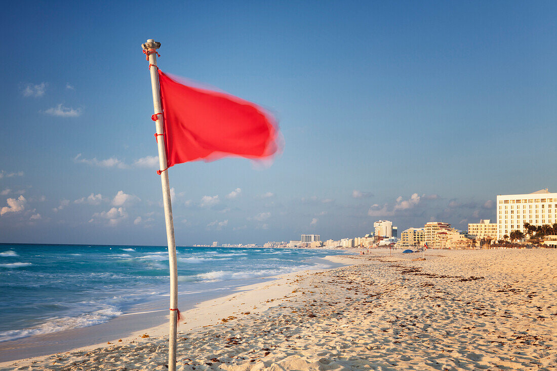 Red flag on beach in hotel zone at Cancun. Signal for no swimming. Coastline.