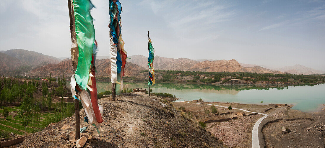 Lunda Poles near Yellow River. View from hilltop over the road. Mountain landscape. Prayer flags fluttering in the wind.