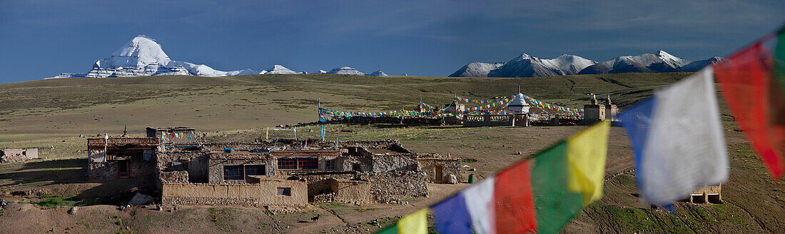 View of Mount Kailash from Chiu Monastery. Small temple and buildings on the plateau. Prayer flags.