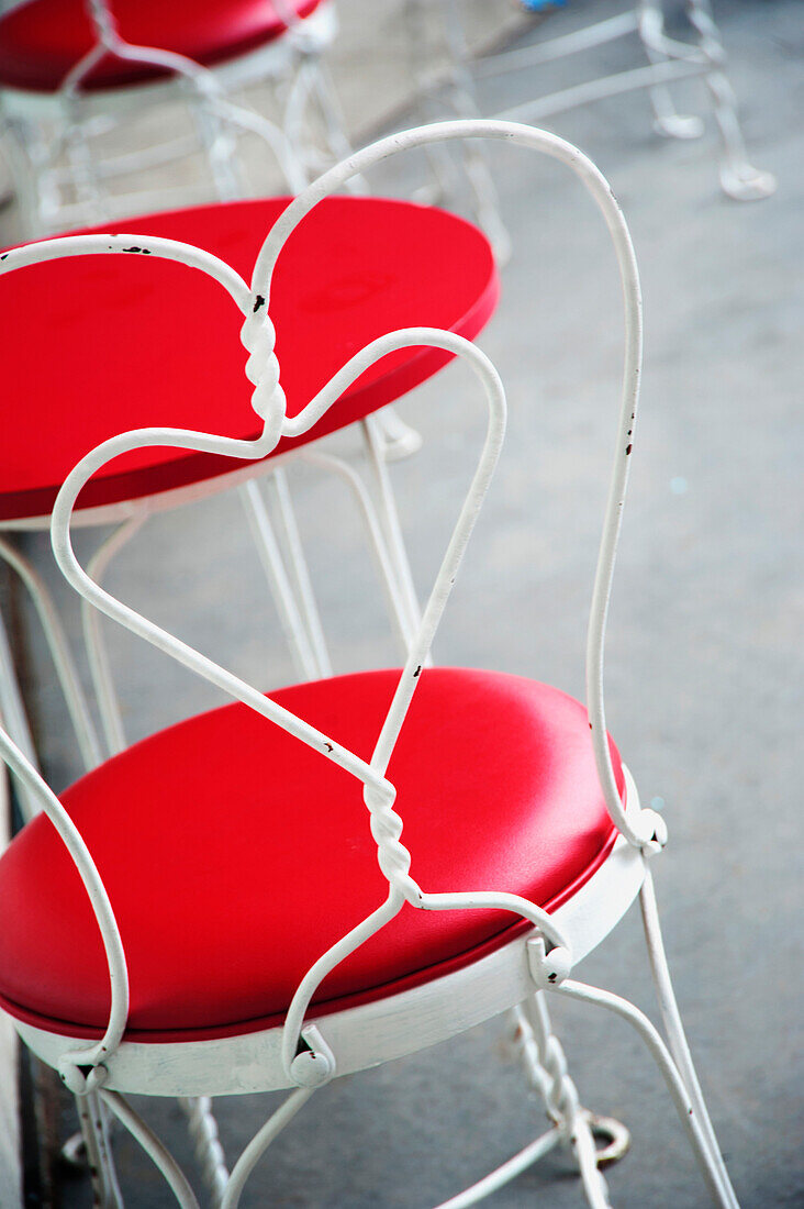North Vancouver, British Columbia, Canada. Cafe chairs, with white metal frames. Heart shaped back. Red padded seat. A red topped circular table.