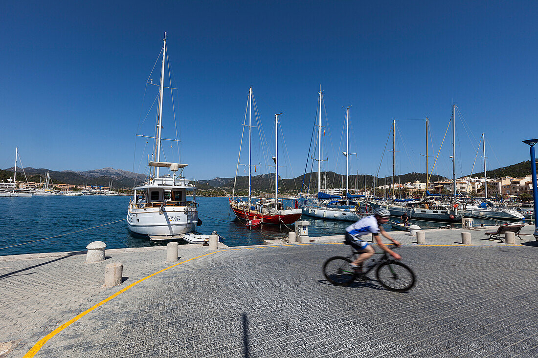 Bicycle rider passing marina, Port d'Andraitx, Andratx, Majorca, Balearic Islands, Spain