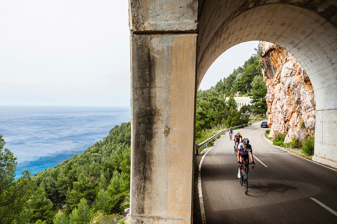 Bike racers in coast road tunnel at Mediterranean Sea, Estellencs, Mallorca, Spain