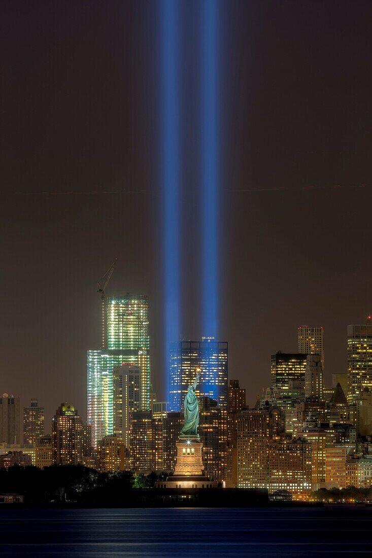 The twin beams of light of the Tribute in Light, an annual memorial to the events of September 11, 2001, shine into the evening sky in New York City on either side of the Statue of Liberty on Tuesday, September 11, 2012