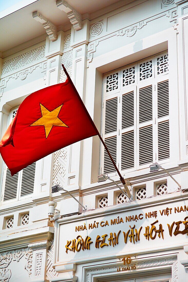 The flag of Vietnam, designed in 1940, waving in front of a Colonial French style building