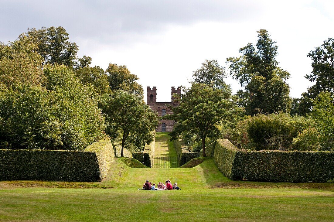 Family having picnic with Belvedere Tower in distance, Claremont Landscape Garden, Esher, Surrey, UK