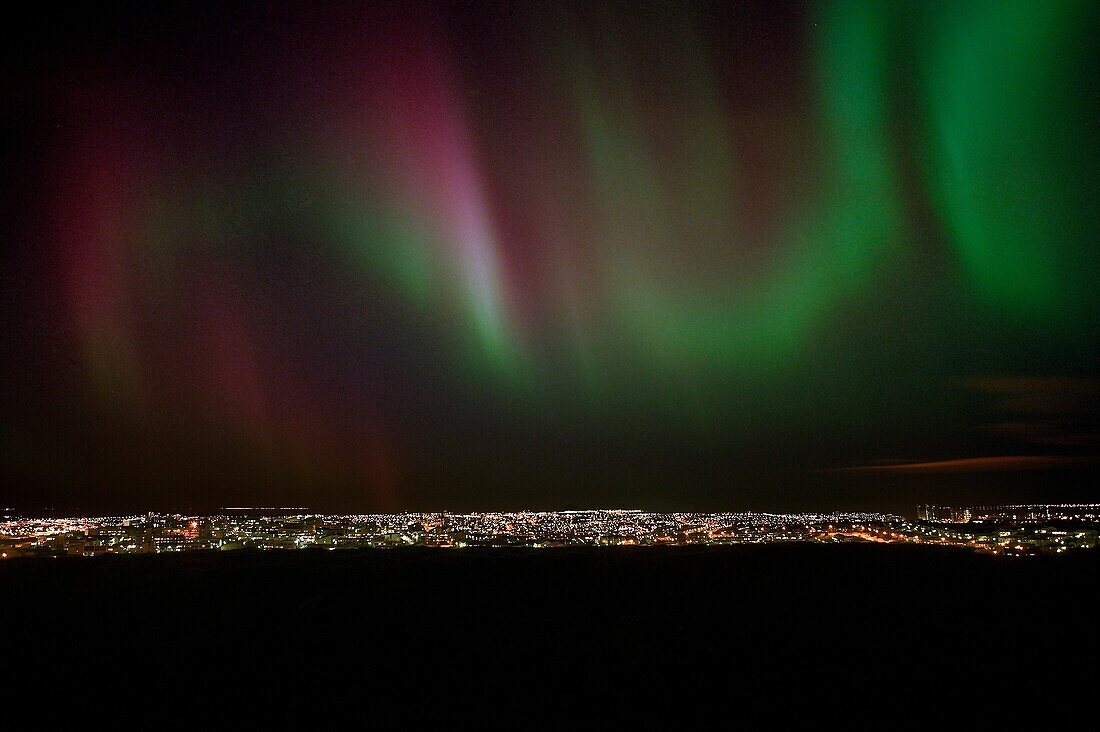 Aurora Borealis over City Lights  Digital composite of city lights and aurora borealis