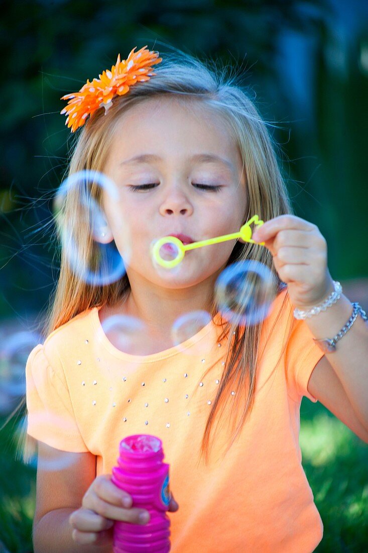 alone, blow, blowing, bubble, child, color image, contrast, female, flower, fun, girl, hair, holding, human, innocence, kid, looking at camera, nature, one, open, Orange, outdoors, people, shade, shirt, single, solo, vertical, vibrant, Vibrant colors, was