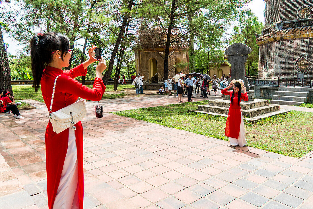 Young girls in traditional clothes at the tomb of the emperor Thien Mu, near the Imperial city of Hue, Vietnam, Asia