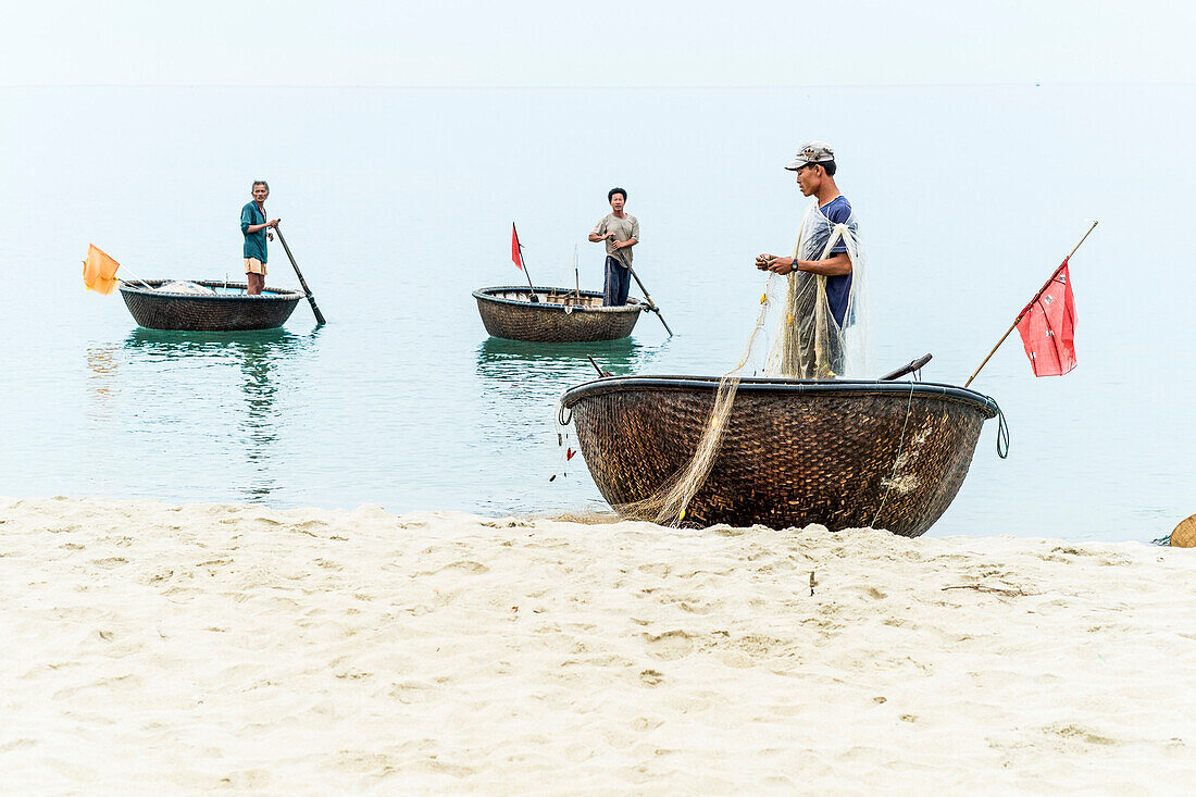 Fischer mit traditionellem Fischerboot am Strand von Hoi An, Vietnam, Asien
