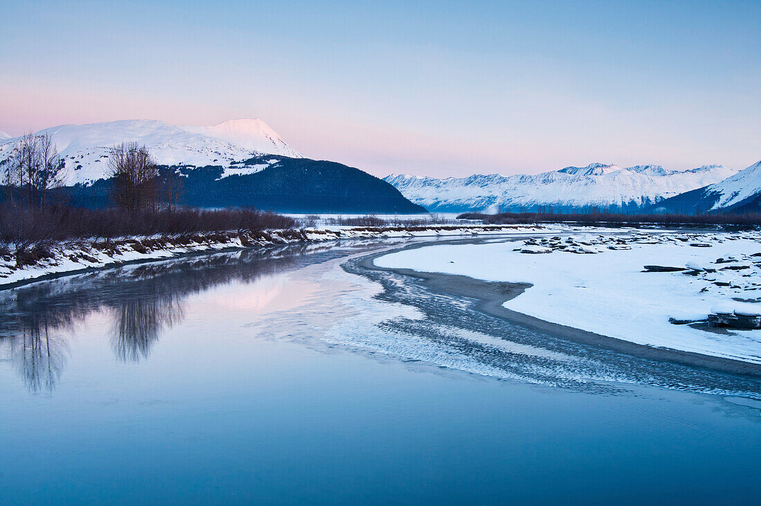 Morning alpenglow on the Kenai Mountains along the Turnagain Arm reflects in the outfall of Portage Creek, Southcentral Alaska, Winter