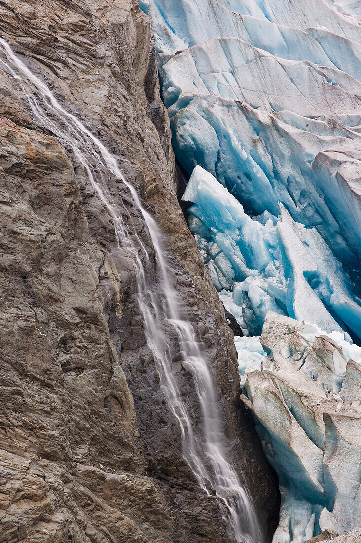 A waterfall flows down bedrock on the edge of Mendenhall Glacier, Juneau, Southeast Alaska, Summer