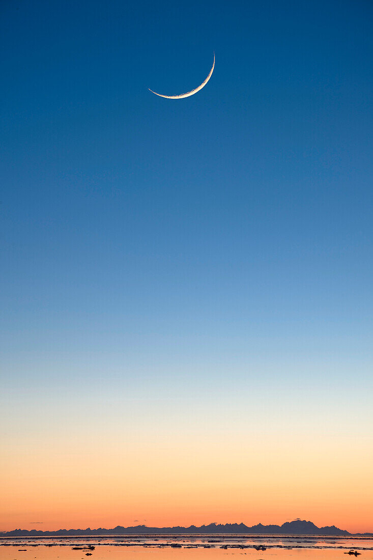 Cresent moon rising at sunset over Cook Inlet near Elderberry Park in Anchorage, Southcentral Alaska, Winter, COMPOSITE