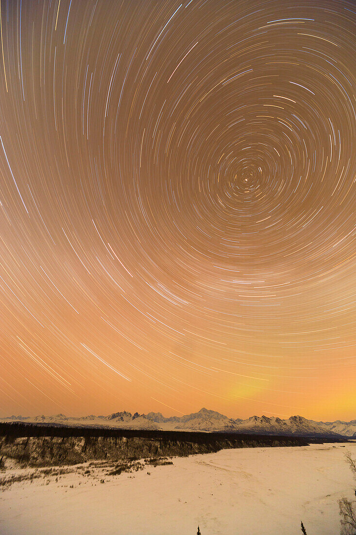 Night time view of star trails over Mt. McKinley with Northern Lights in the background, Denali State Park, Southcentral Alaska, Winter