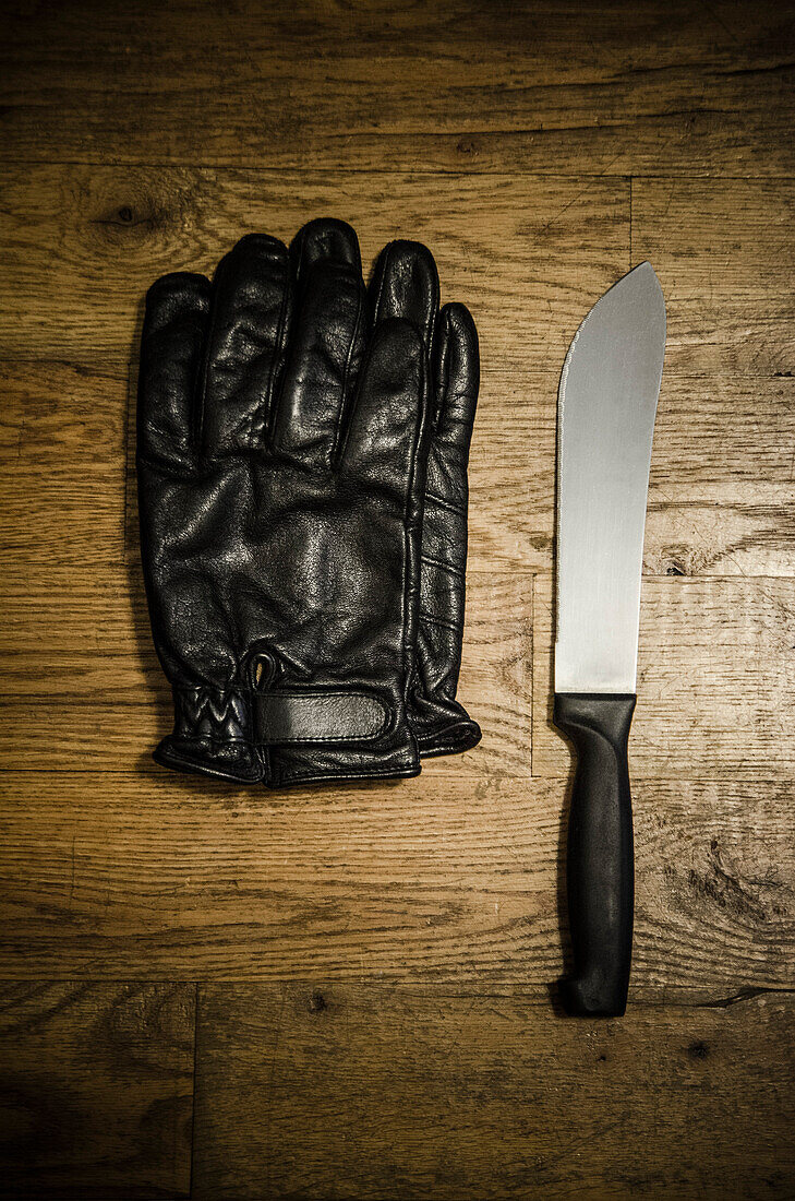 Pair of Black Leather Gloves and Knife on Wood Floor