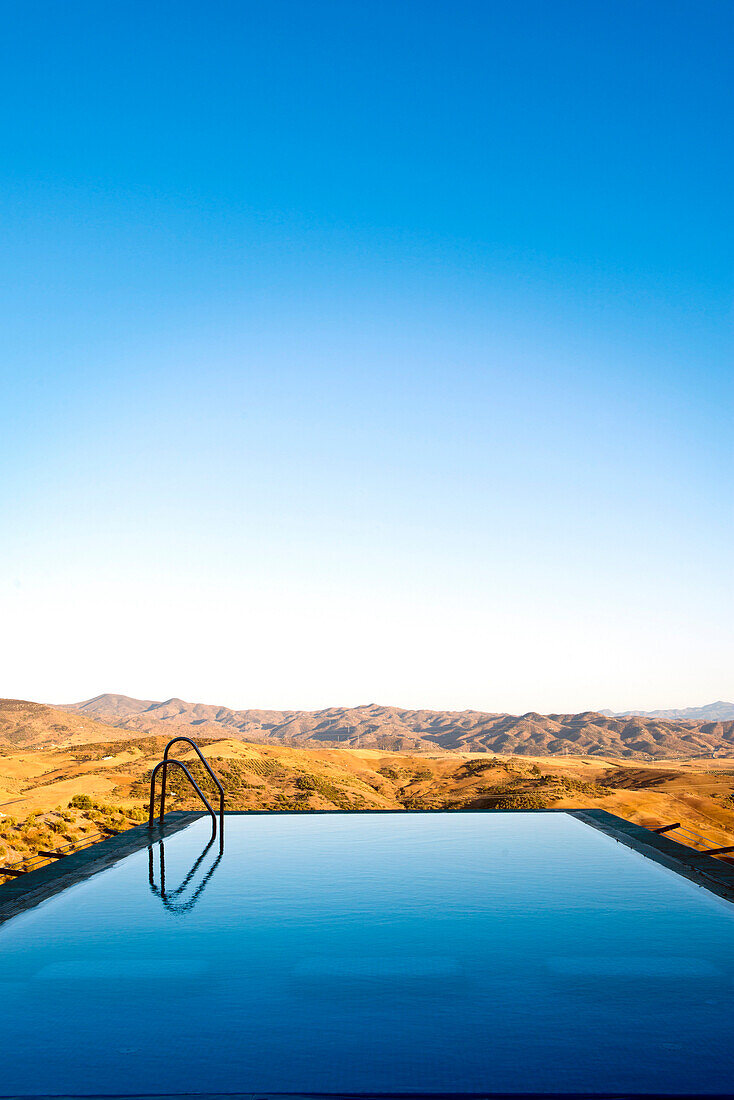 An infinity water pool with steps with a view over the Andalucian mountains in Spain. Late summer afternoon.