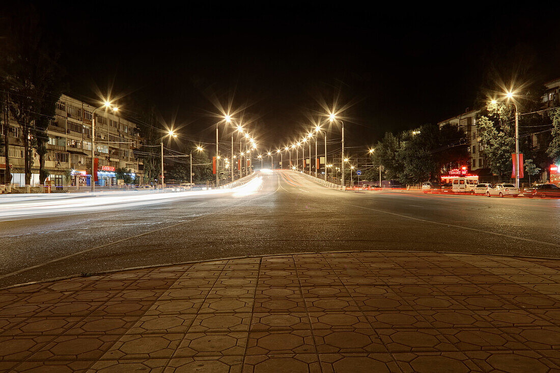 The major city of the Republic of Dagestan at night. A bridge over railroad lit up. Deserted street.