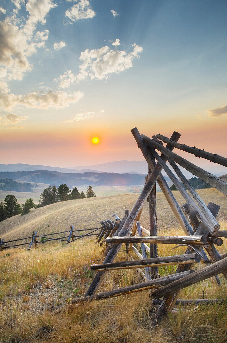 Strong log stock fence in ranch lands, Sunset over the mountains and valleys of Montana