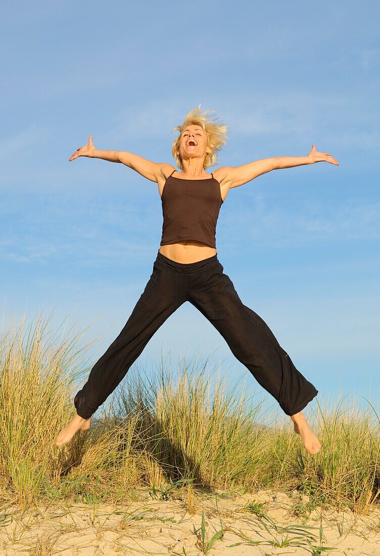 Mature Woman Jumping For Joy On Beach
