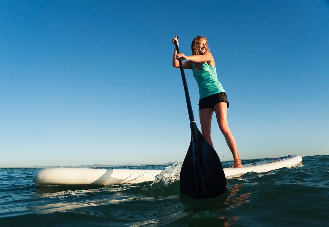 A Woman Paddling While Standing On A Surf Board Off Dos Mares Beach, Tarifa, Cadiz, Andalusia, Spain