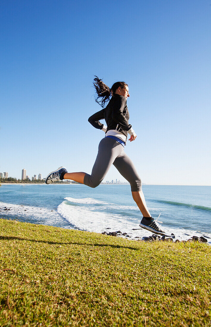 A young woman running by the water's edge, gold coast queensland australia