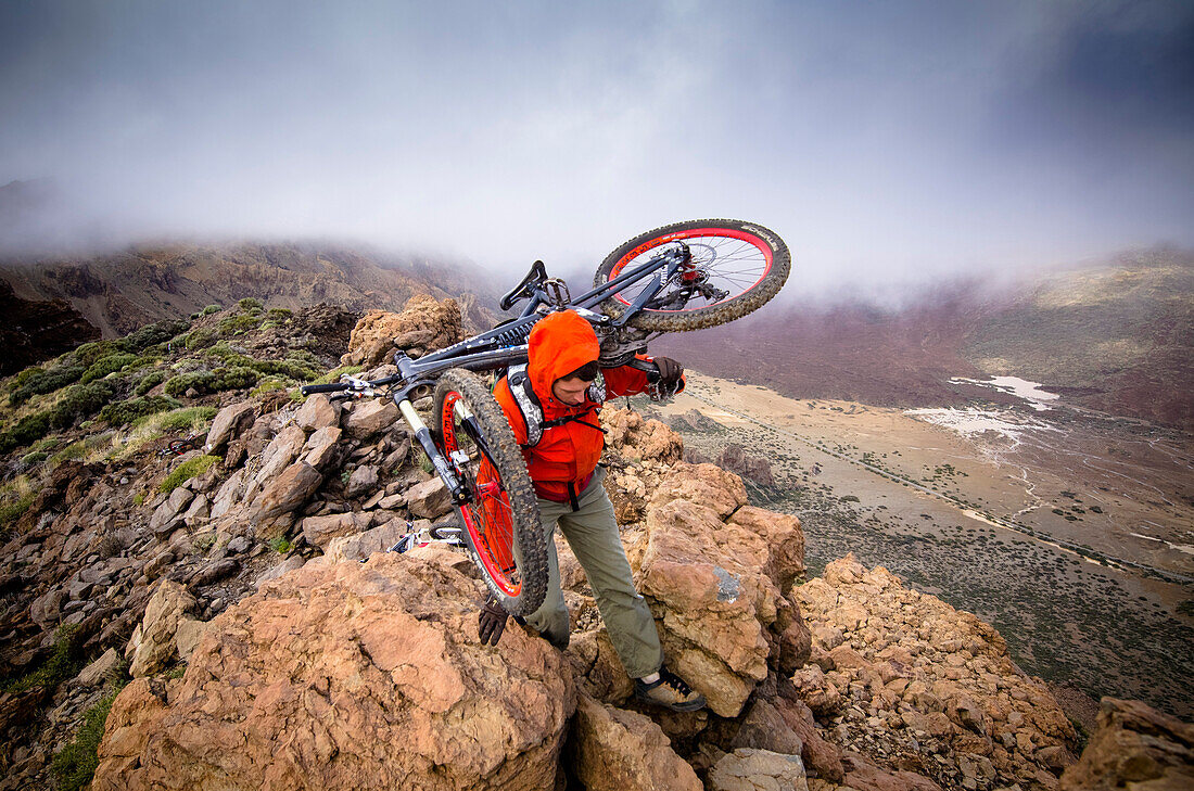 Mann trägt mountainbike über grat, Teneriffa