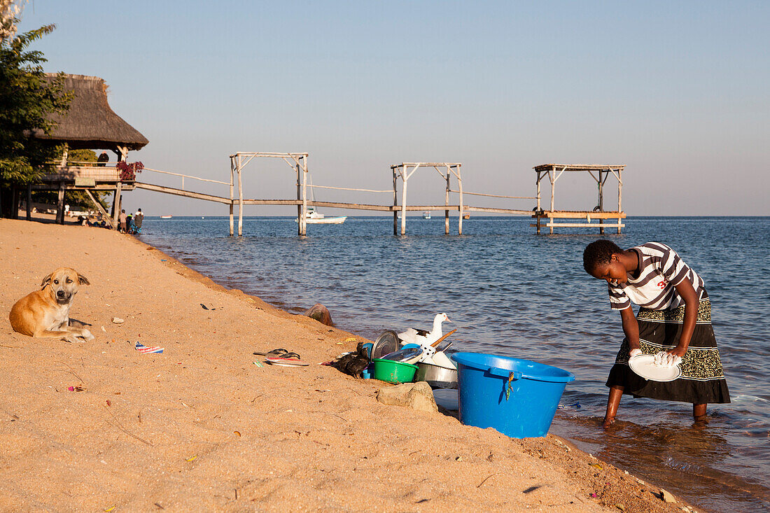 A girl washing the dishes on the beach of Lake Malawi, Chembe Village, Cape Mclear, Africa