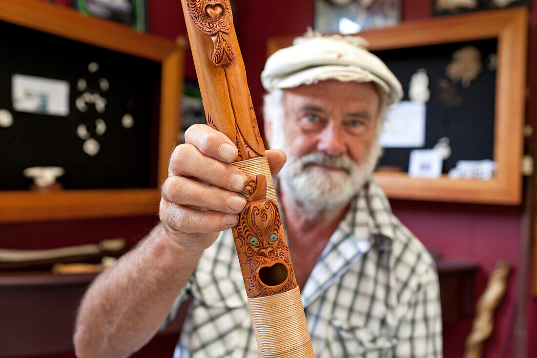 blocked for illustrated books in Germany, Austria, Switzerland: Master carver Brian Flintoff with wooden carved, mythical figures on a flute, Instrument maker, Maori Music, South Island, New Zealand