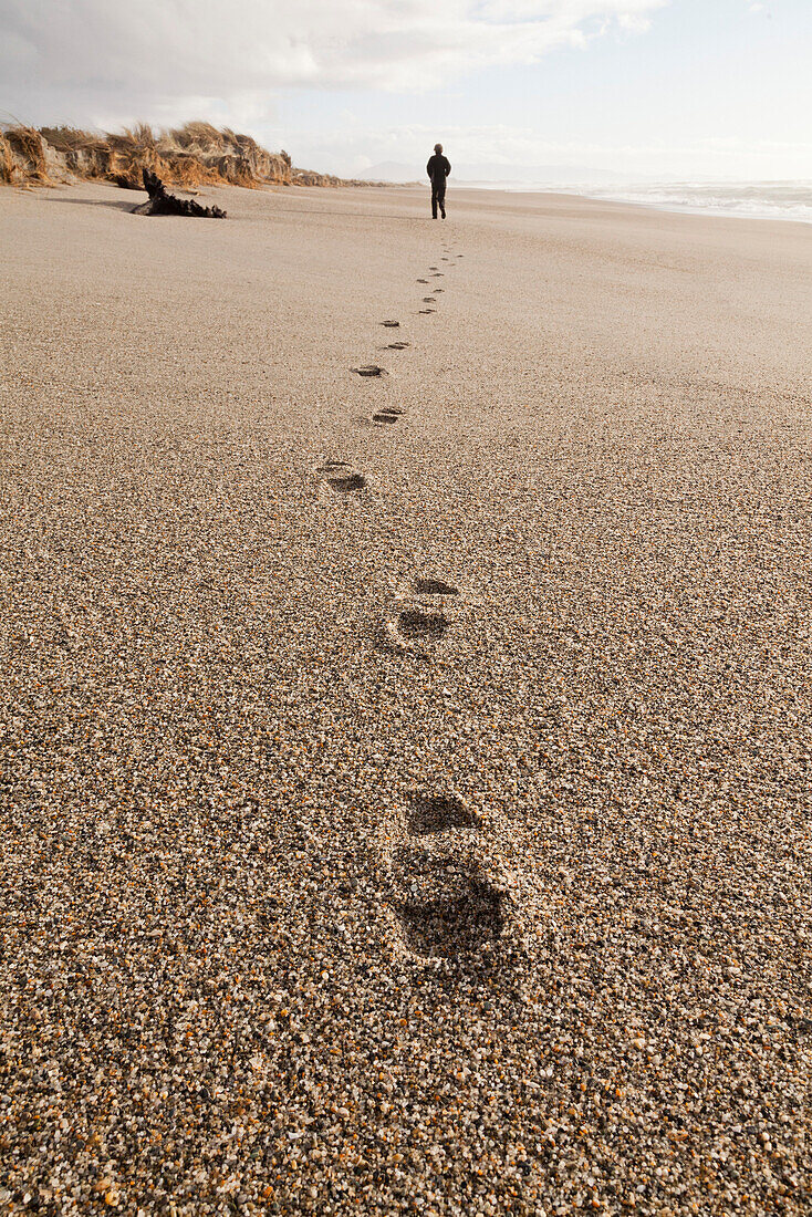 Footprints in coarse sand, person walking along the beach, autumn, South Island, New Zealand