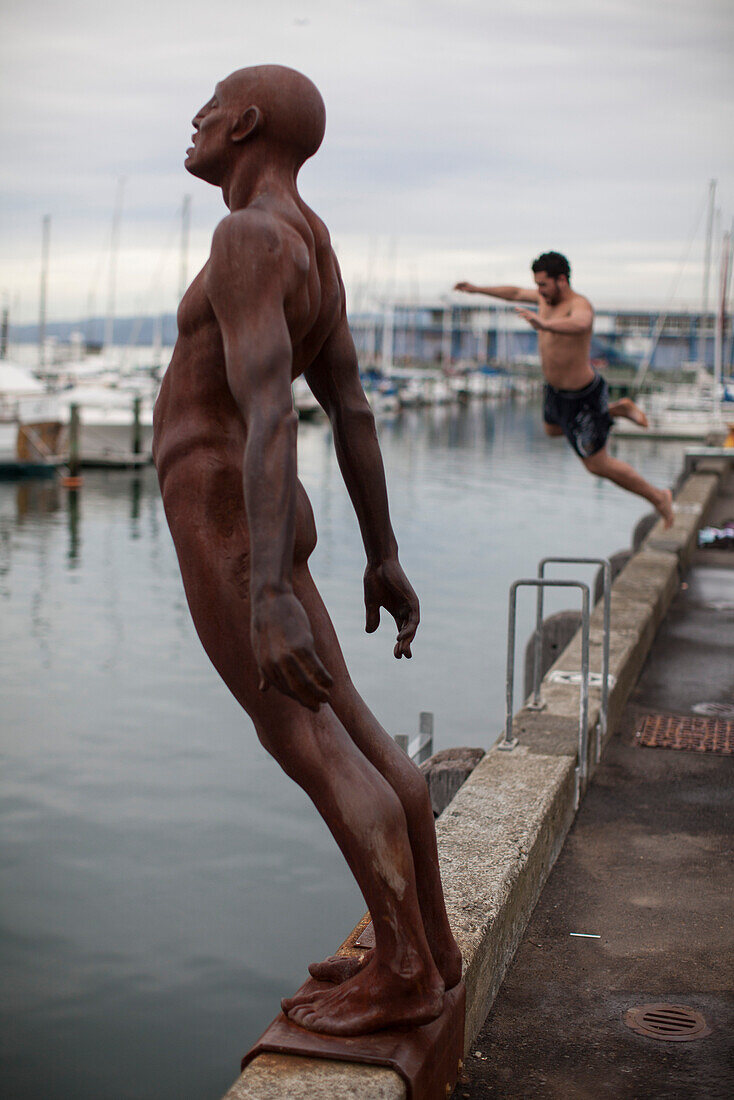 Waterfront with statue Max Patte's Solace of the Wind and swimmer, Wellington, North Island, New Zealand