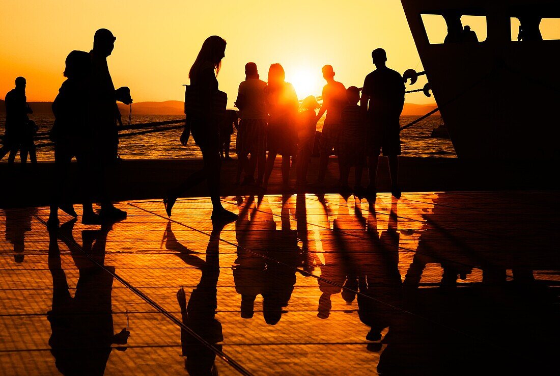 People enjoying the sunset on a warm summer evening at the Sun Salutation on the ground in Zadar, Croatia  Designed by architect Nikola Basic, it harvests sun during the day and puts on a light show in the evening using the rhythm of the waves