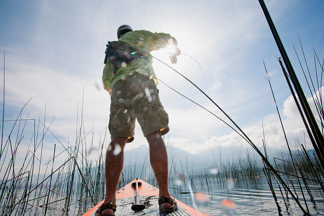 Man Flyfishing on Paddle Board on Lake