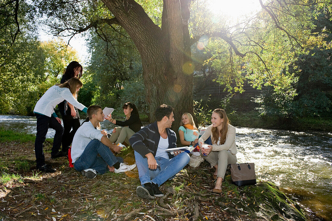Gruppe junger Leute lernt am Ufer der Dreisam, Freiburg im Breisgau, Schwarzwald, Baden-Württemberg, Deutschland