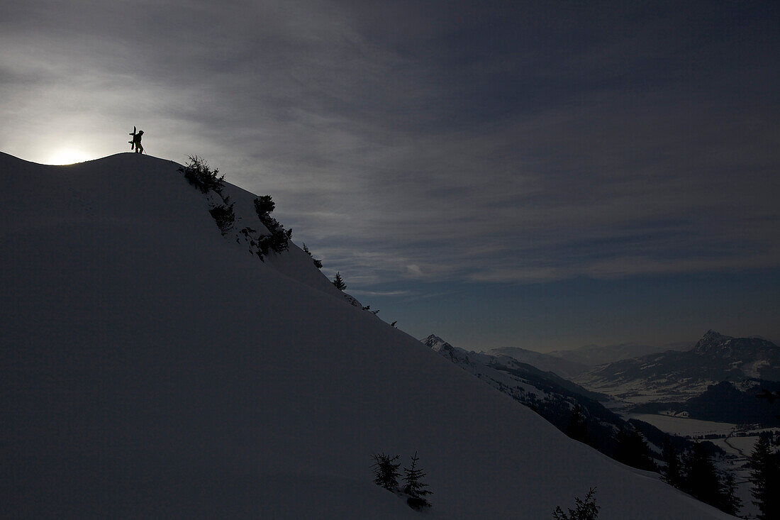 Snowboarder steht auf Berggipfel, Hahnenkamm, Tirol, Österreich