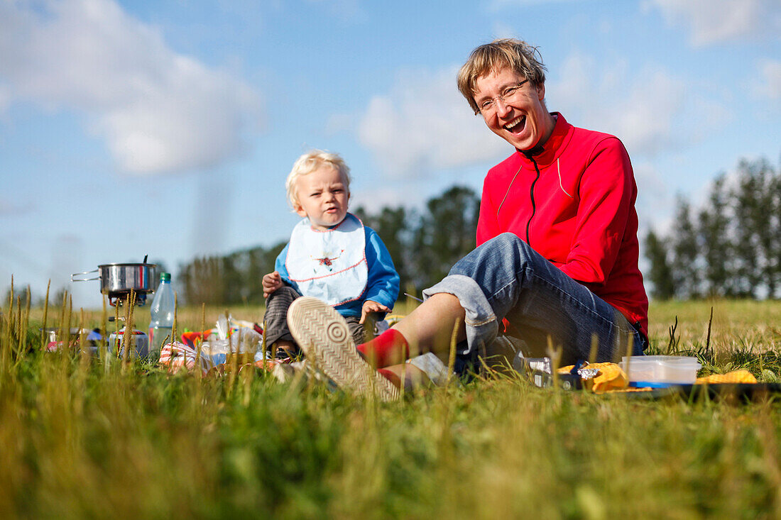 Mother and her son (2 years) having breakfast on a meadow, Altefaehr, Island of Ruegen, Mecklenburg-Western Pomerania, Germany