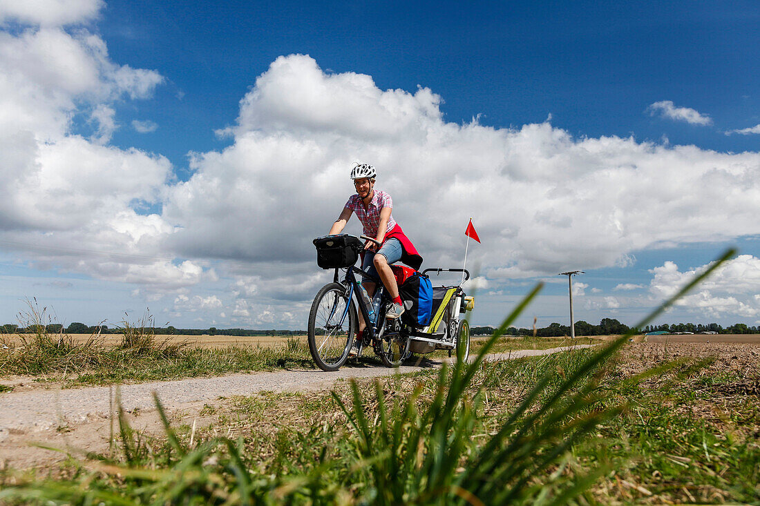 Women cycling with child transporter along a dirt track, Altefaehr, Island of Ruegen, Mecklenburg-Western Pomerania, Germany