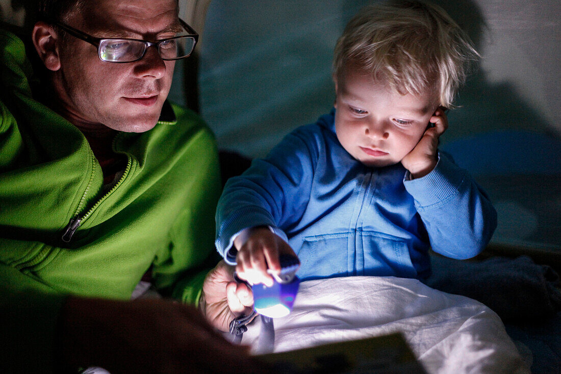 Vater liest Sohn (2 Jahre) eine Geschichte in einem Zelt vor, Haide, Ummanz, Insel Rügen, Mecklenburg-Vorpommern, Deutschland