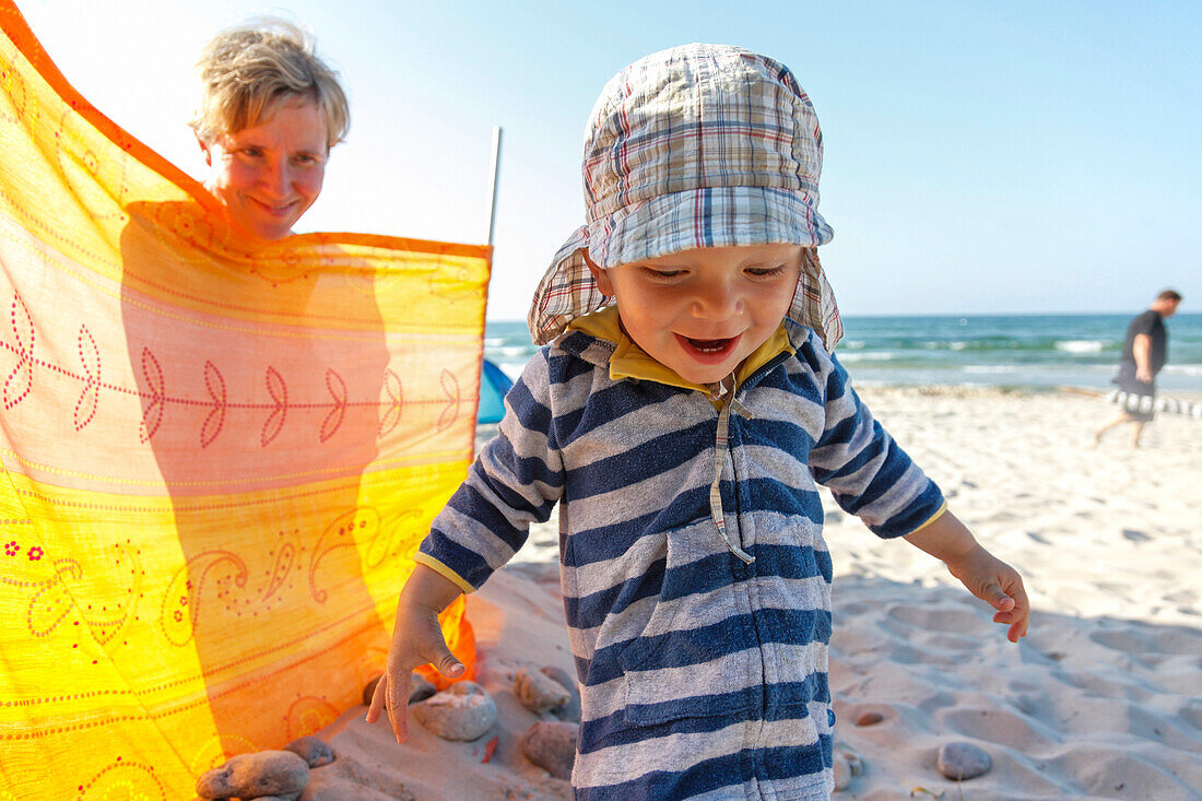 Boy (2 years) playing at beach, mother behind a windbreak, Bakenberg, Wittow Peninsula, Island of Ruegen, Mecklenburg-Western Pomerania, Germany