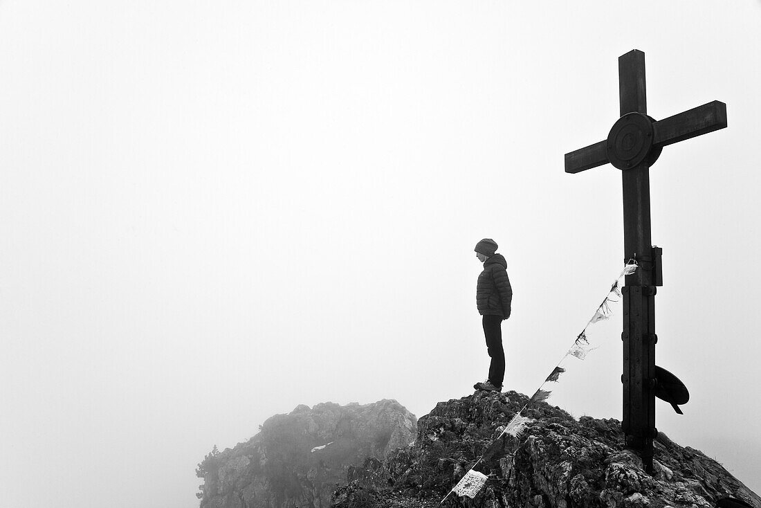 Woman on the summit of Buchstein, summit corss with prayer flags, Tegernseer hut, Kreuth, Bavaria, Germany