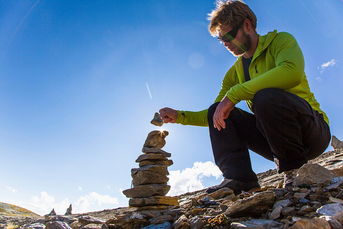 Mann legt einen Stein auf einen Steinmann, Johannishütte, Virgental, Tirol, Österreich