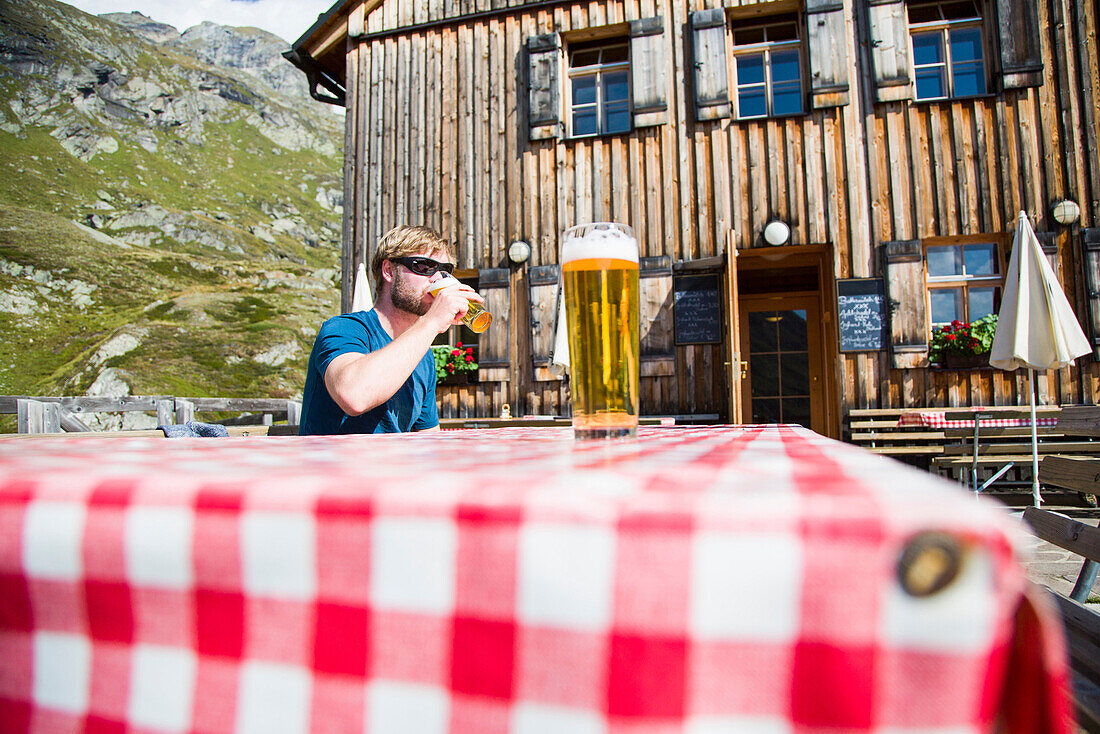 Man drinking a glass of beer on a terrace, Johannis Hut, Virgen Valley, Tyrol, Austria