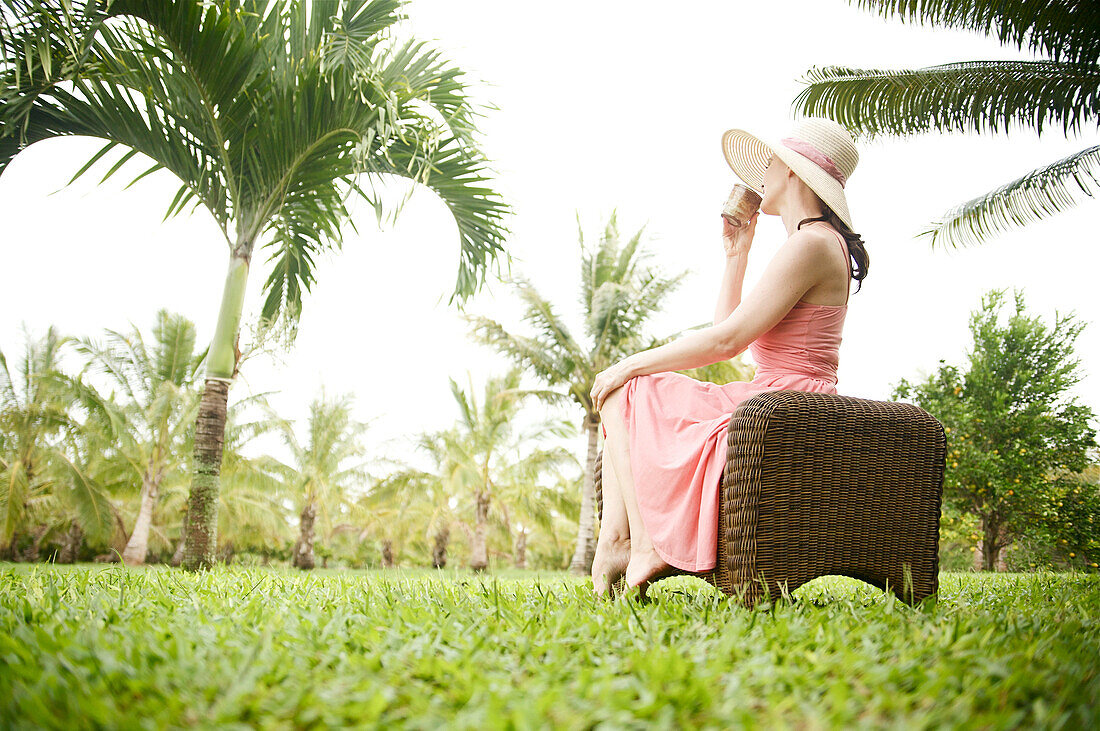 Hawaii, Kauai, Portrait of a beautiful woman in a pink sundress drinking tea.