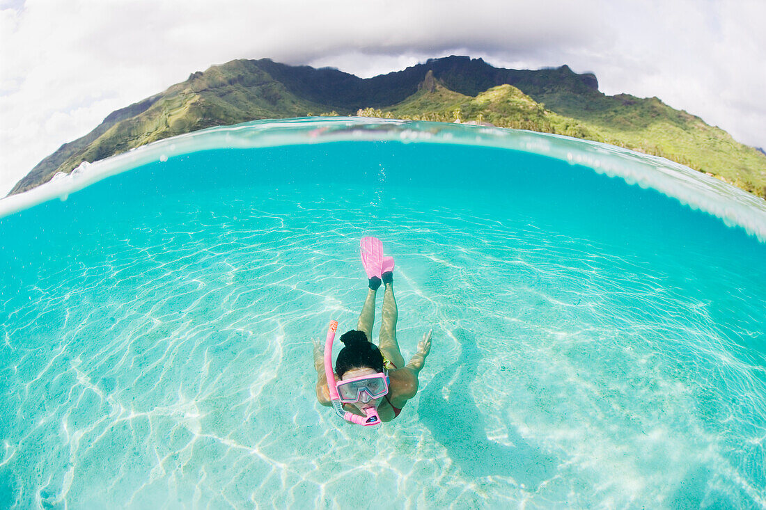 French Polynesia, Moorea, Woman free diving in turquoise ocean.