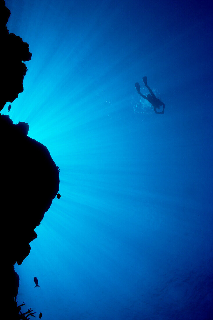 Micronesia, Yap, Light rays shining through reef canyon, Diver in distance.